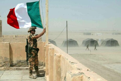 Una immagine di archivio mostra un militare italiano mentre fissa il tricolore nella base italiana