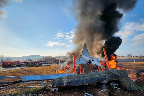 Fire and smoke rise from the tail section of a Jeju Air Boeing 737-800 series aircraft