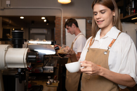 Una giovane barista prepara un cappuccino foto iStock.