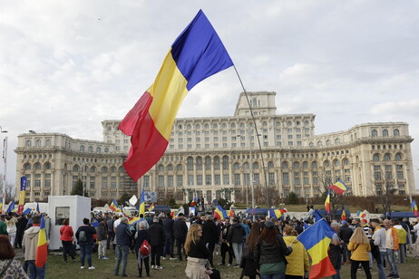 Calin Georgescu supporters wave placards and national flags while shouting slogans during a protest