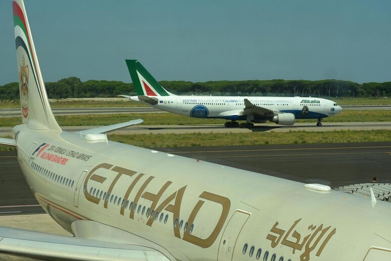 Un aereo della compagnia Etihad con uno dell 'Alitalia sullo sfondo all 'aeroporto di Fiumicino, 18 luglio 2014 - RIPRODUZIONE RISERVATA