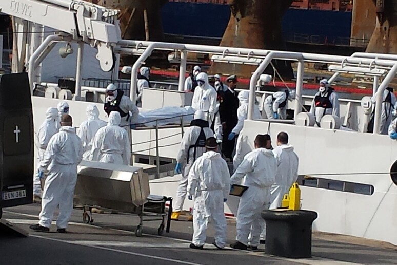 Volontari e forze dell 'ordine maltesi portano a terra le prime salme da una imbarcazione nel porto di La Valletta a Malta - RIPRODUZIONE RISERVATA