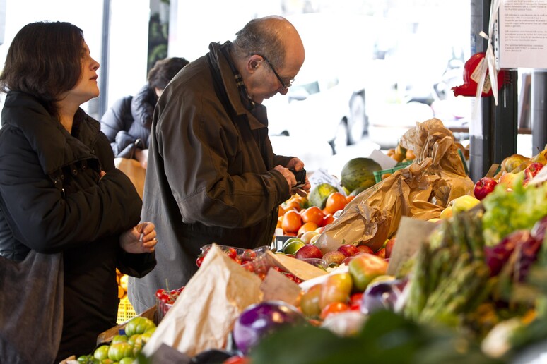 Un uomo e una donna acquistano frutta e verdura in un mercato rionale a Roma. Foto di archivio - RIPRODUZIONE RISERVATA