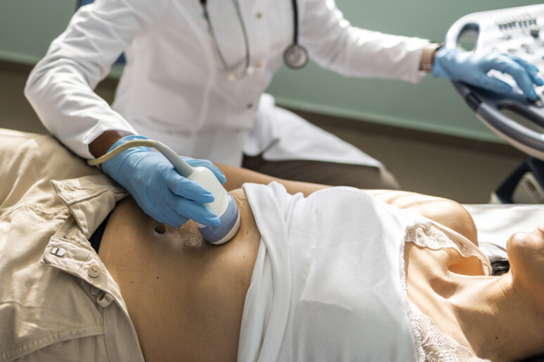 Doctor examining mature woman with ultrasound scanner device - RIPRODUZIONE RISERVATA