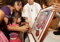 Una mamma filippina mostra la foto di Giovanni Paolo II in una chiesa a Manila